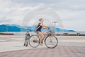 Happy family is riding bikes outdoors and smiling. Mom on a bike and son on a balancebike