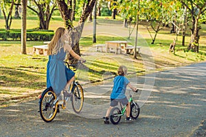 Happy family is riding bikes outdoors and smiling. Mom on a bike and son on a balancebike