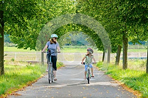 Happy family is riding bikes outdoors and smiling. Mother and daughter, cute little preeschool girl on bicycles, active leisure