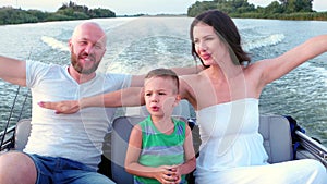 Happy family riding on a boat, parents with a child having fun summer day, quickly go along the river by speedboat