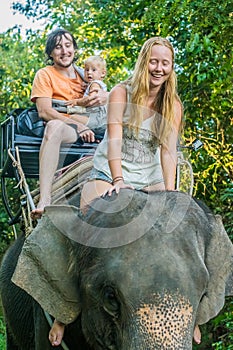 Happy family riding on an elephant, woman sitting on the elephant`s neck