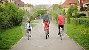 Happy Family Riding On Their Bikes At The Park On A Sunny Day. They Have A Lot of Fun Together.