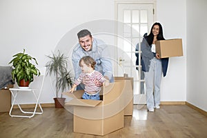 Happy Family Riding Their Son In Cardboard Box While On Moving Day