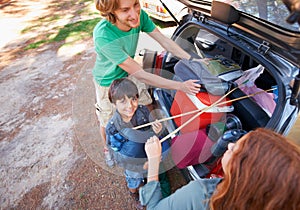 Happy family, road trip and packing car trunk for camping, holiday or vacation above in nature outdoors. Top view of dad