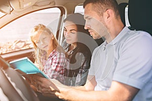 Happy family on a road trip in their car. Dad, mom and daughter are traveling by the sea or the ocean or the river