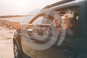 Happy family on a road trip in their car. Dad, mom and daughter are traveling by the sea or the ocean or the river