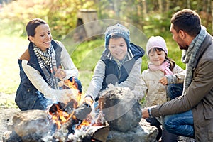 Happy family roasting marshmallow over campfire