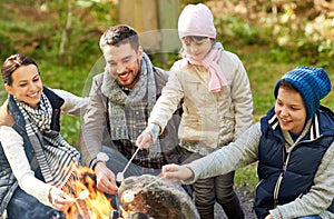 Happy family roasting marshmallow over campfire