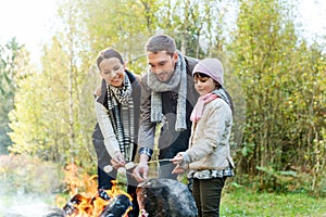 Happy family roasting marshmallow over campfire