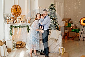 happy family in the room in front of sofa, the fireplace and Christmas tree.