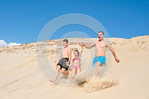 Happy family run cheerfully on the beach sand. Family outdoor sports games. Active healthy lifestyle concept