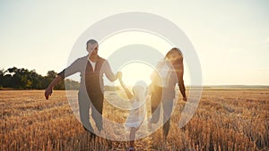 Happy family run in the field throw up their daughter. kid dream concept. daughter and parents run across a wheat field