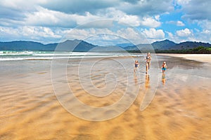 Happy family run by wide sand beach