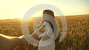 Happy family running across field holding hands. beautiful girl with her daughter walks on field with wheat, holding her