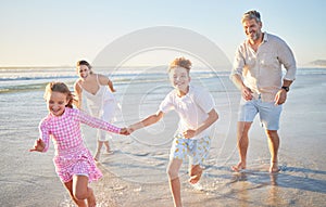 Happy family running on the beach with mother, father and children holding hands for summer holiday, wellness and