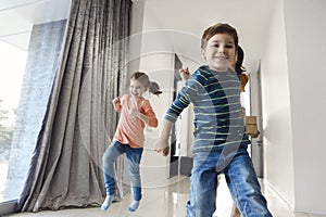 Happy family running in hall. Funny kids jumping  with carton box, parents laughing