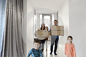 Happy family running in hall. Funny kids jumping  with carton box, parents laughing