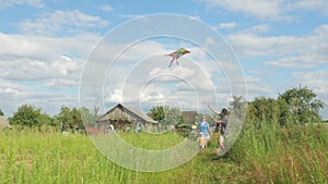 Happy family running with a kite on green grass to the camera. Mother, father and baby 2 years in summer