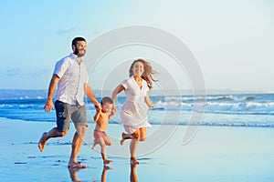 Happy family running by sunset beach