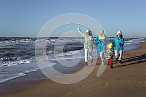 A happy family runs along the seashore. A little boy with his mother, sister and grandmother. Love, tenderness and activity in the