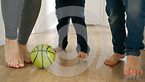 Happy family's feet as they kick a football back and forth on a wooden floor in a house corridor