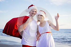 Happy family in Santa Claus hats celebrating Christmas on beach. Smiling people traveling to warm countries on winter