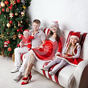 Happy family in Santa costumes celebrating Christmas.