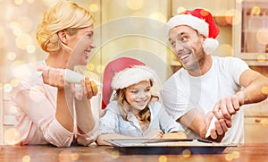 Happy family in santa helper hats making cookies