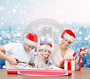 Happy family in santa helper hats packing gift