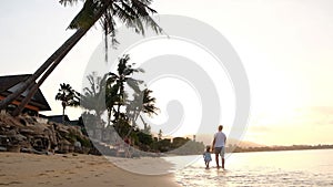 Happy family on sea beach at resort. Father and children walking alone the beach at the sunset time. Tropical summer