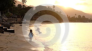 Happy family on sea beach at resort. Little girl playing on the beach at the sunset time. Tropical summer vacations