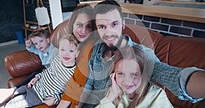 Happy family selfie together, young Caucasian father and mother taking photo with three children at home slow motion.