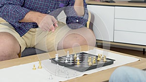 Happy family with senior father playing chess with son together with enjoy on sofa at home.