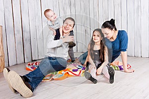 Happy family sit with toys on colorful blanket on the floor.