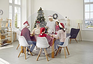 Happy family sitting around table, enjoying Christmas lunch and having fun together