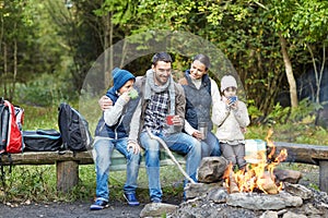 Happy family sitting on bench at camp fire