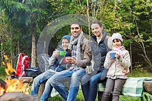 Happy family sitting on bench at camp fire