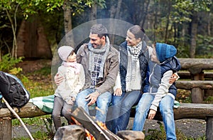 Happy family sitting on bench at camp fire