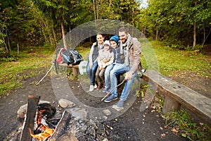 Happy family sitting on bench at camp fire