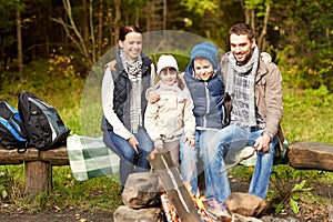 Happy family sitting on bench at camp fire