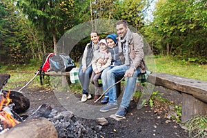 Happy family sitting on bench at camp fire