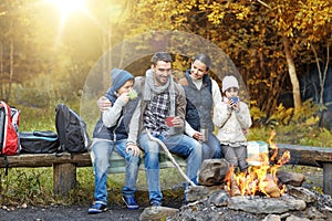 Happy family sitting on bench at camp fire