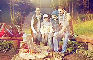 Happy family sitting on bench at camp fire