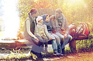 Happy family sitting on bench and talking at camp