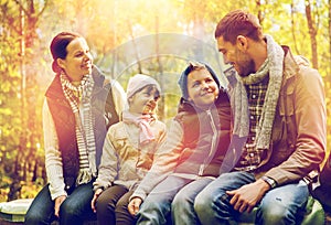 Happy family sitting on bench and talking at camp