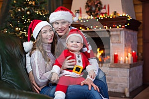 Happy family sitting on couch at home in front of fireplace in festive Christmas room