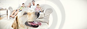 Happy family sitting on couch with their pet yellow labrador in foreground