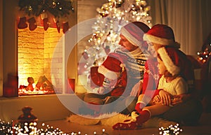 Happy family sitting by fireplace on Christmas Eve