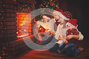 Happy family sitting by fireplace on Christmas Eve