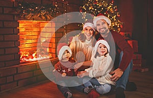Happy family sitting by fireplace on Christmas Eve